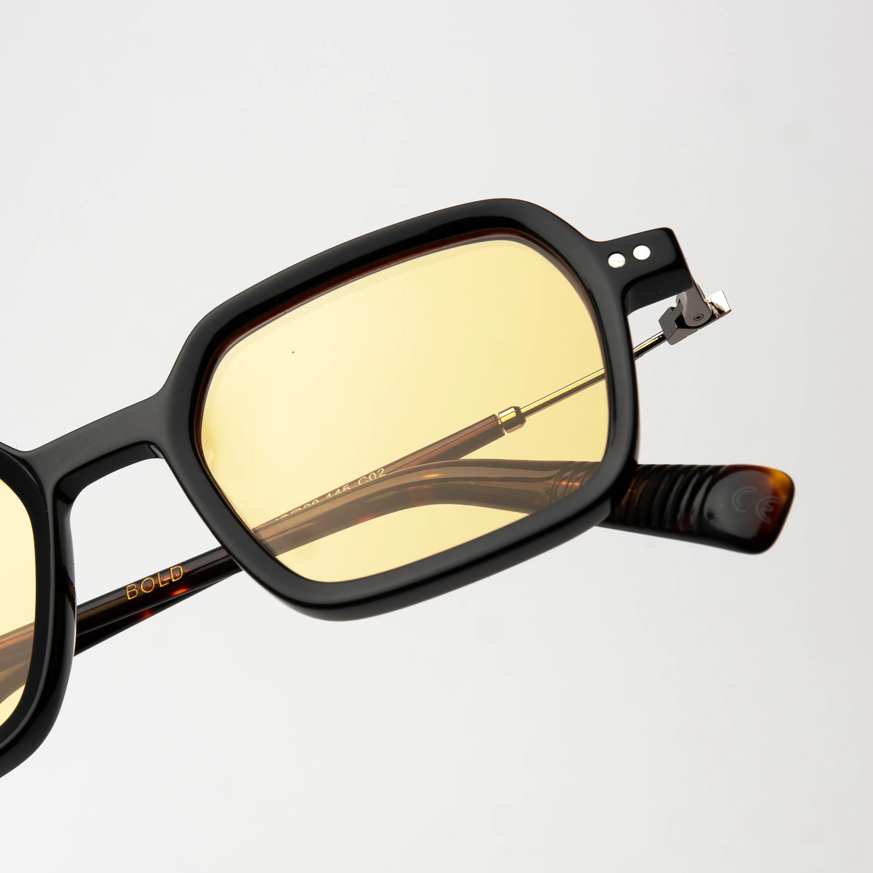 Bold Carey Sunglasses with a close-up of the hinge detail on the carey frame and amber polarized lens.