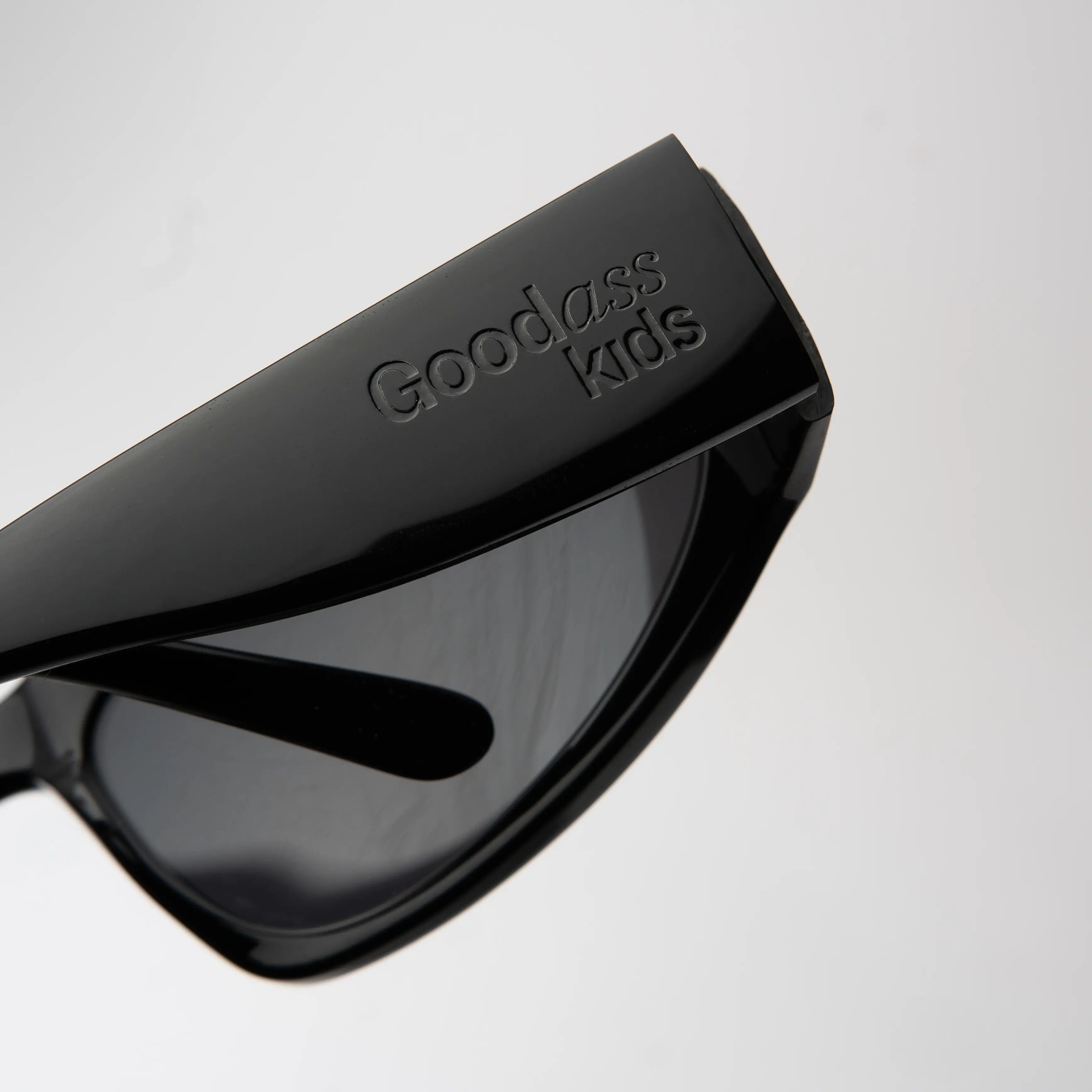 Icon Black Sunglasses with a close-up of the hinge detail on the matte black frame and smoke lens.
