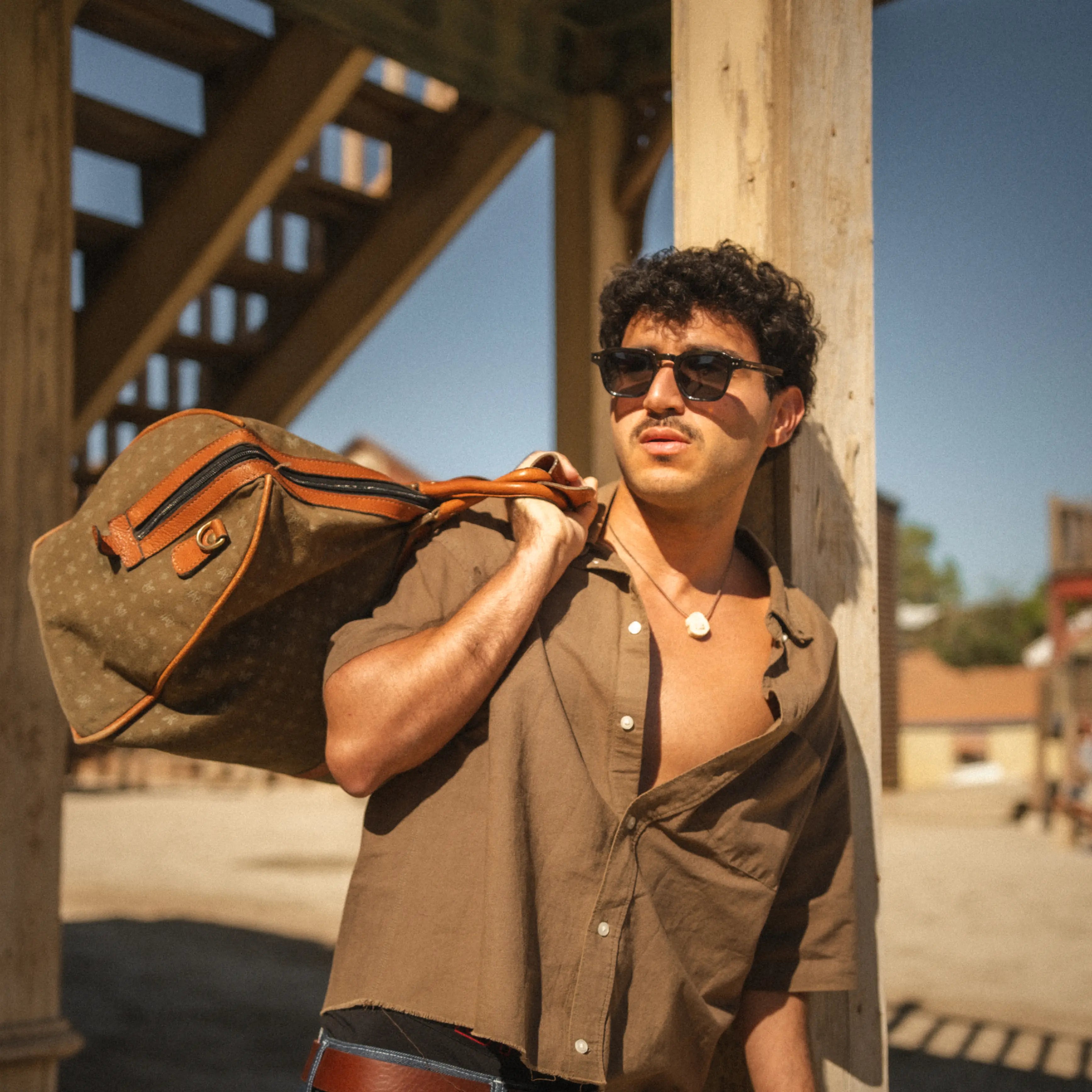 Model wearing Outlaw Carey Sunglasses outdoors, tortoiseshell frame and smoke polarized lenses for effortless street style.