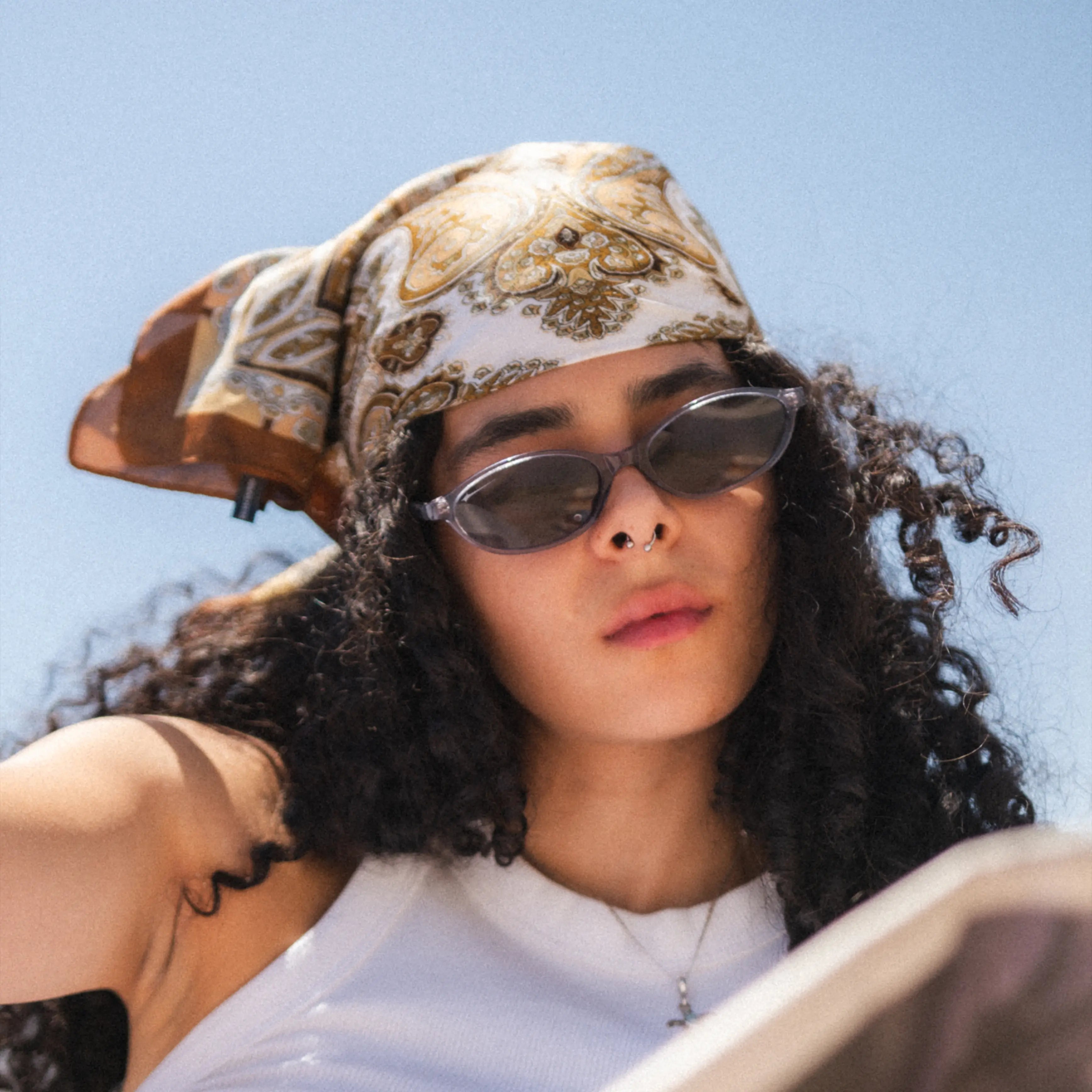 Model wearing Timeless Silver Sunglasses with a stylish scarf against a clear blue sky.